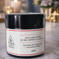 Jar of Mango Body Butter with black lid on a marble surface, blurred background with flowers and candles.