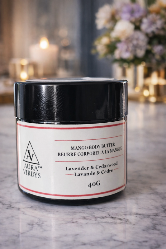 Jar of Mango Body Butter with black lid on a marble surface, blurred background with flowers and candles.