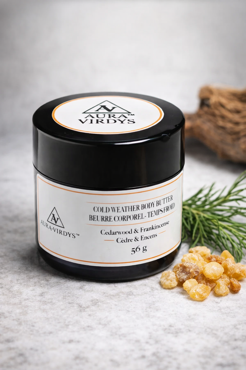 Jar of Aura Virdys cold weather body butter with ingredients on a textured surface