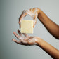 Hands holding a bar of soap against a gray background